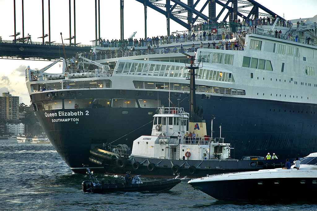  A tug guides the QE2 stern-first towards the terminal. 